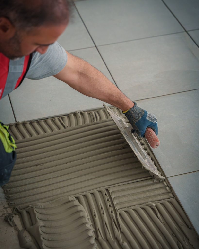 Pose de carrelage avec application de colle sur le support.