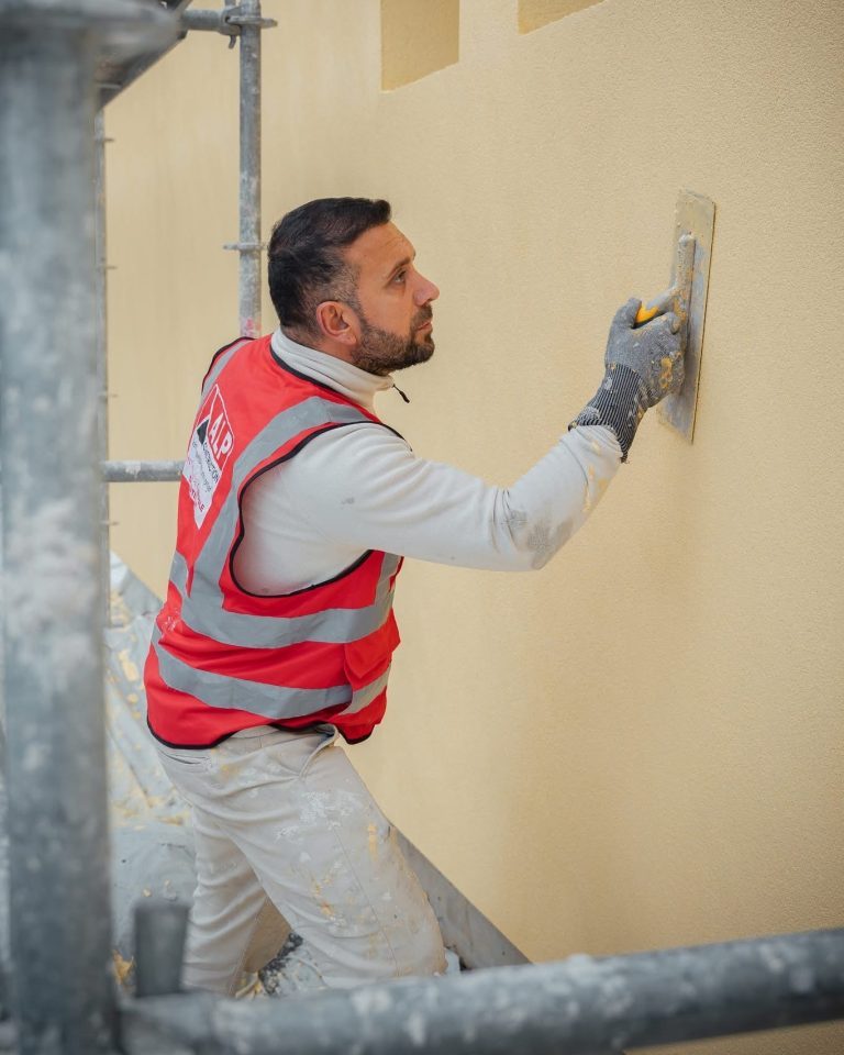 &Eacute;quipe ALP au travail : fa&ccedil;ades et enduits, avec le logo ALP visible sur les v&ecirc;tements.
