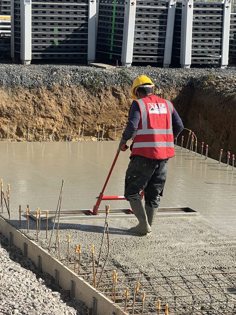 Équipe ALP au travail : béton et maçonnerie, avec le logo ALP visible sur les vêtements.