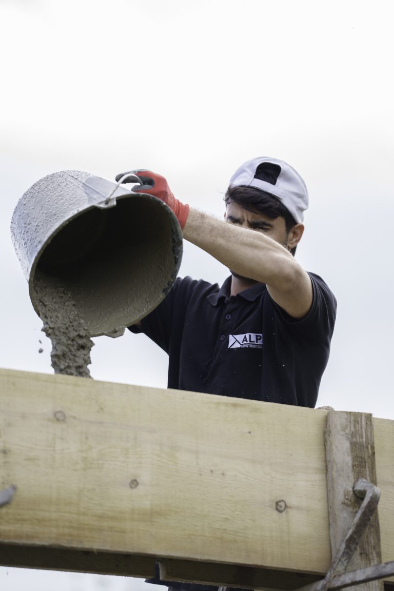 Équipe ALP au travail : béton et maçonnerie, avec le logo ALP visible sur les vêtements.