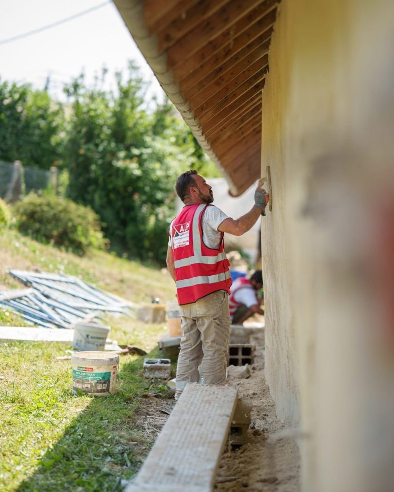 Deux salariés ALP travaillent sur un enduit de façade sous une avancée de toit.